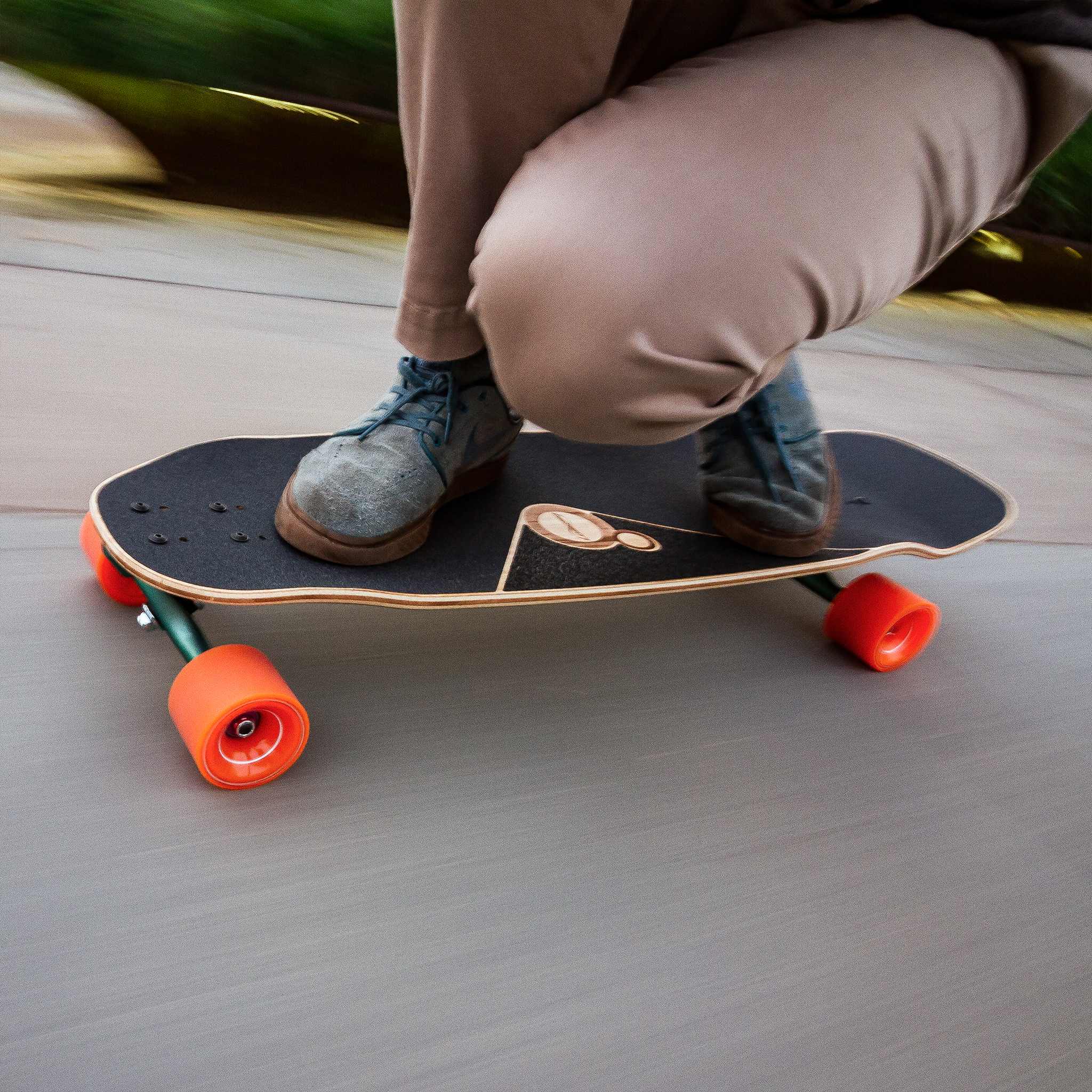 Close-up of a rider's feet on a longboard rolling on orange Orangatang 4President 70mm wheels with motion blur