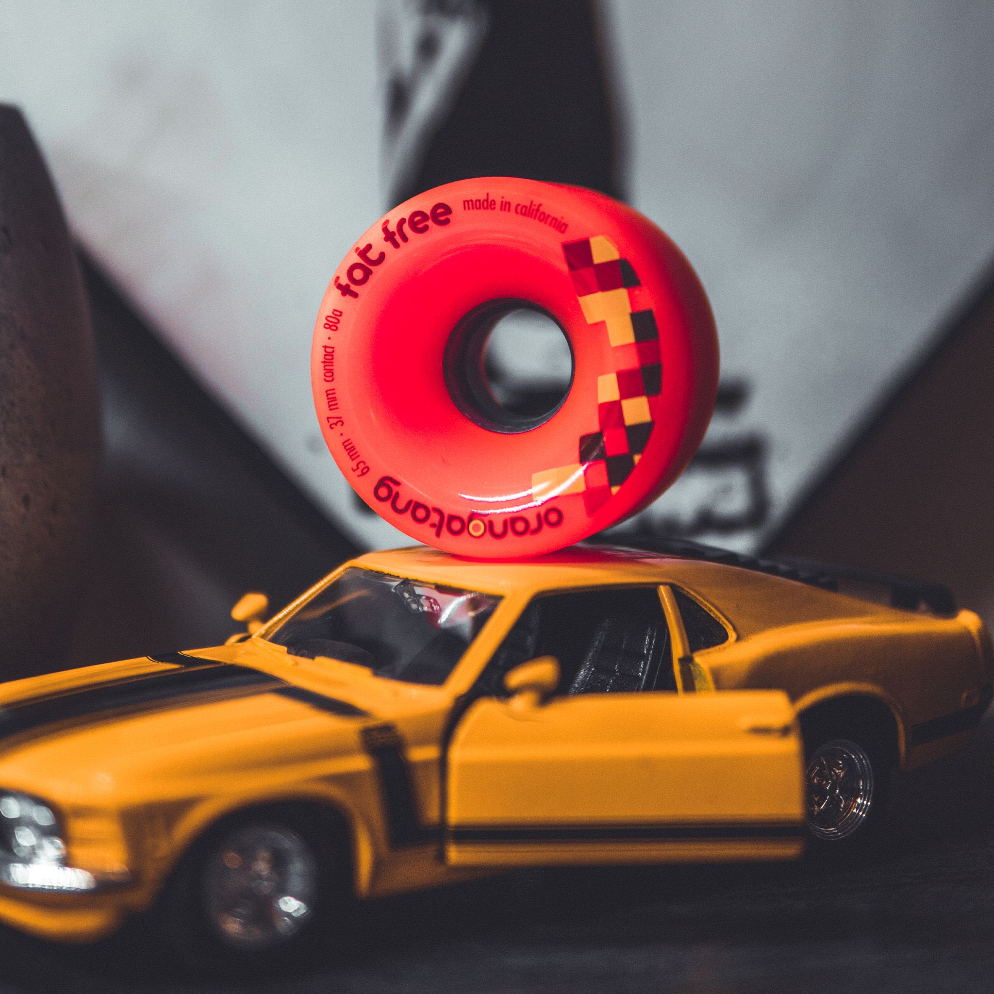 Red Orangatang Fat Free 65mm wheel balanced on the roof of a toy orange muscle car