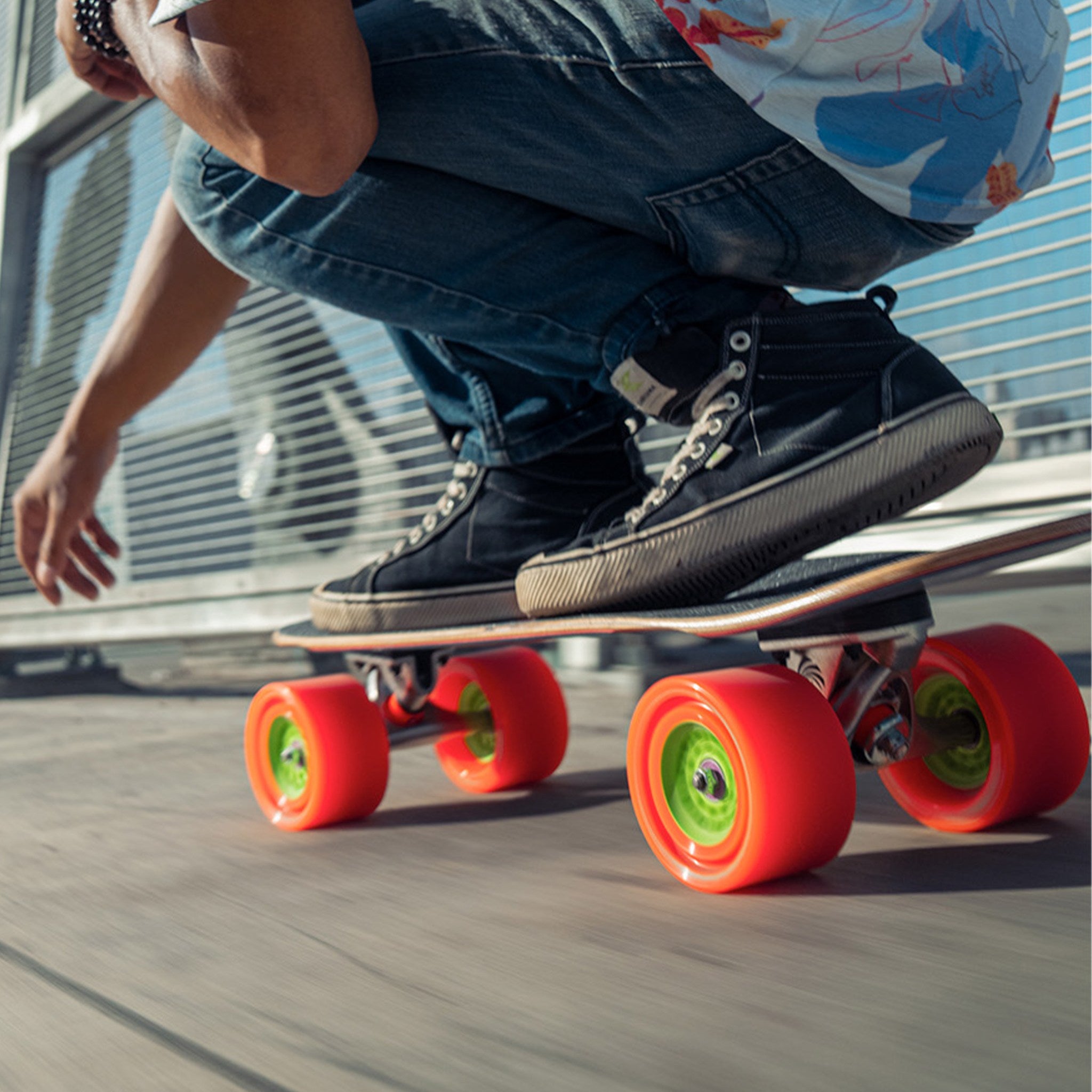 Rider in black high-tops crouched low on a longboard rolling on orange Orangatang Dad Bod 105mm wheels